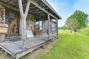 Une cabane rustique en rondins de bois, dotée d’un porche, d’un panneau indiquant un point de dépôt de courrier et d’un atelier de peinture.