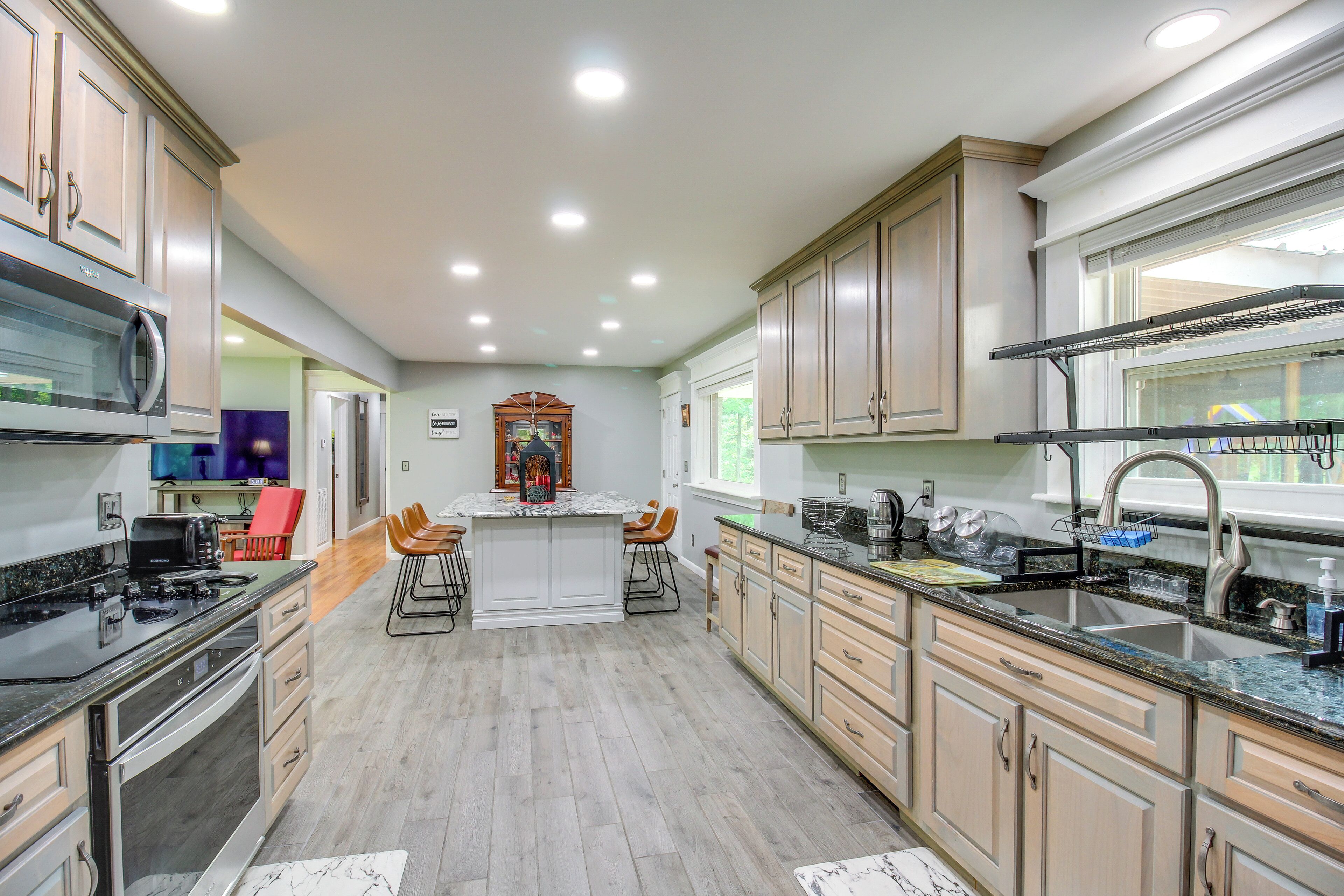 A modern kitchen with a central island, stainless steel appliances, and light wood cabinets.