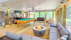 A spacious indoor area with a pool table, a fire pit, and a comfortable seating area.