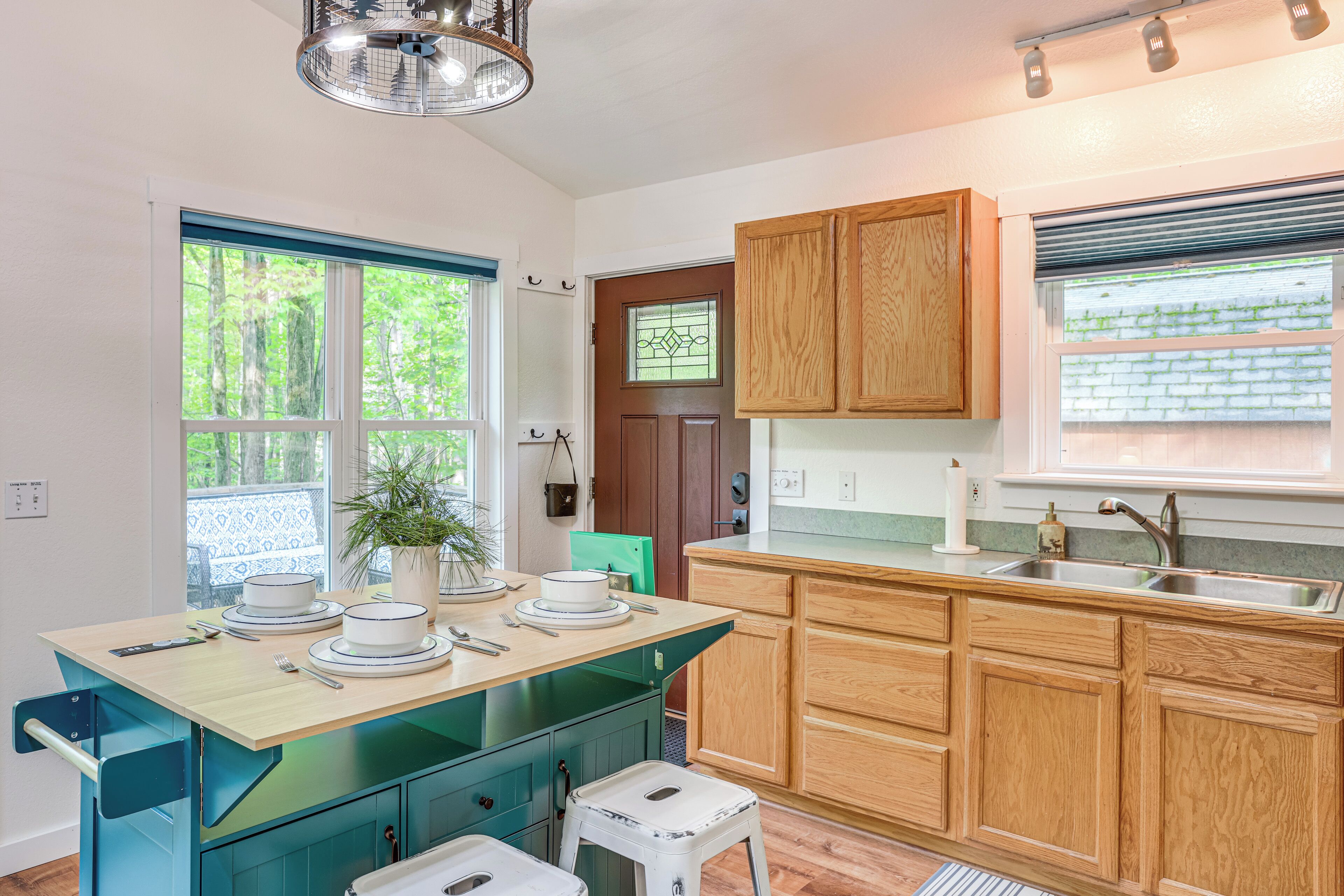 A kitchen with a wooden countertop, a sink, and cabinets. There is a window with a view of trees and a door with a window.