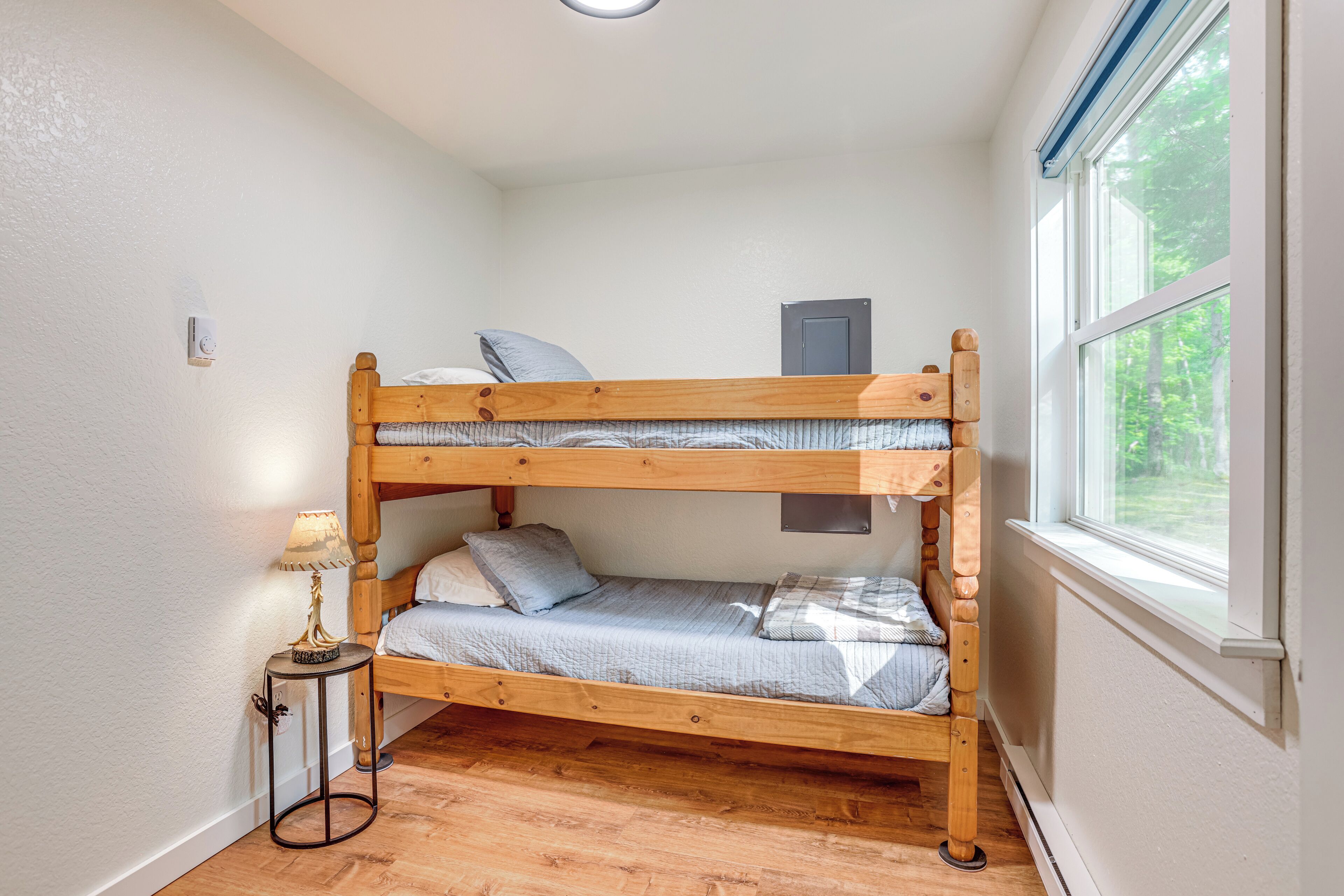 A bunk bed room with a small table and a window.