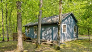 Une cabane dotée d’une véranda, entourée d’arbres.