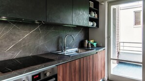 A modern kitchen with a black countertop, stainless steel appliances, and wooden cabinets.