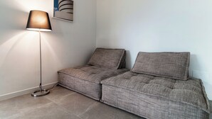 A corner of a room with a floor lamp, a sofa, and a framed picture on the wall.