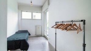 A bedroom with a bed, a radiator, a window, and a drying rack.