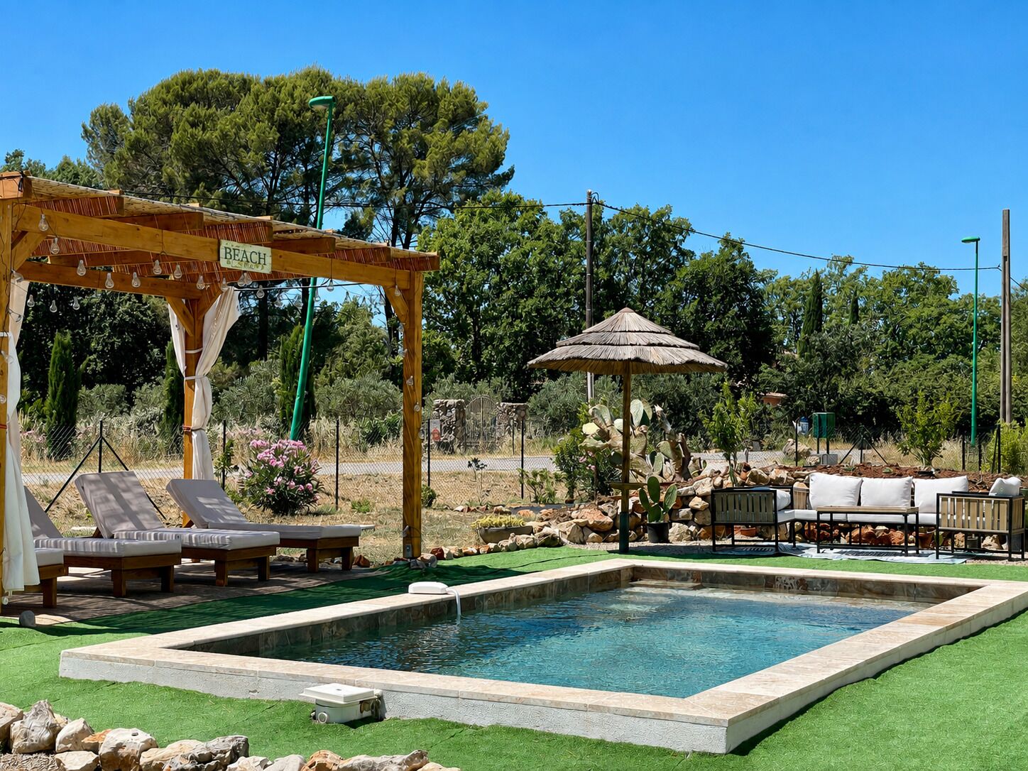 A pool area with lounge chairs, a pergola, and a shaded seating area.