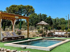 Ein Poolbereich mit Liegestühlen, einer Pergola und einer schattigen Sitzgelegenheit.