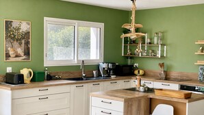 A modern kitchen with white cabinetry, a wooden countertop, a built-in island with a bar stool, and a hanging light fixture. - Lorgues: 3-BR house, private pool, A/C & fiber Wi-Fi (Lorgues)