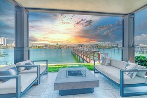 A modern outdoor seating area with a view of a waterfront and sunset. - Incredible Views, Pool/Spa, Dock, Fishing, Walk to beach/Check out Specials! (Clearwater Beach)