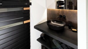 Ein modernes Badezimmer mit einem schwarzen Waschbecken, einem Spiegel und einer schwarz-weißen Waschtischplatte.