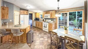 A kitchen with wooden cabinets, a dining area with a table and chairs, a refrigerator, a microwave, and a stove. - 3BR-2BA , Amazing Outdoors, Fully Fenced Yard (Rehoboth Beach)