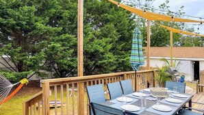 A wooden deck with a table set for four, surrounded by chairs. - 3BR-2BA , Amazing Outdoors, Fully Fenced Yard (Rehoboth Beach)
