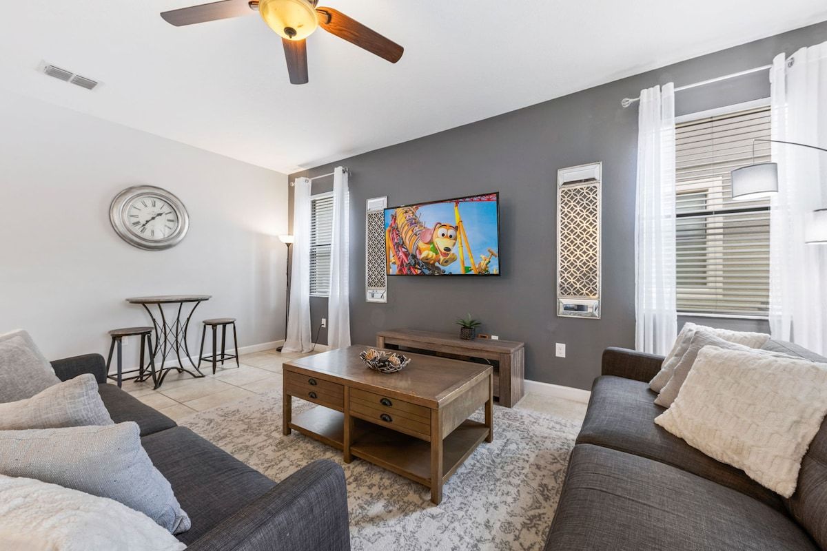 Un salon comprenant un canapé, une table basse, un téléviseur et un ventilateur de plafond.
