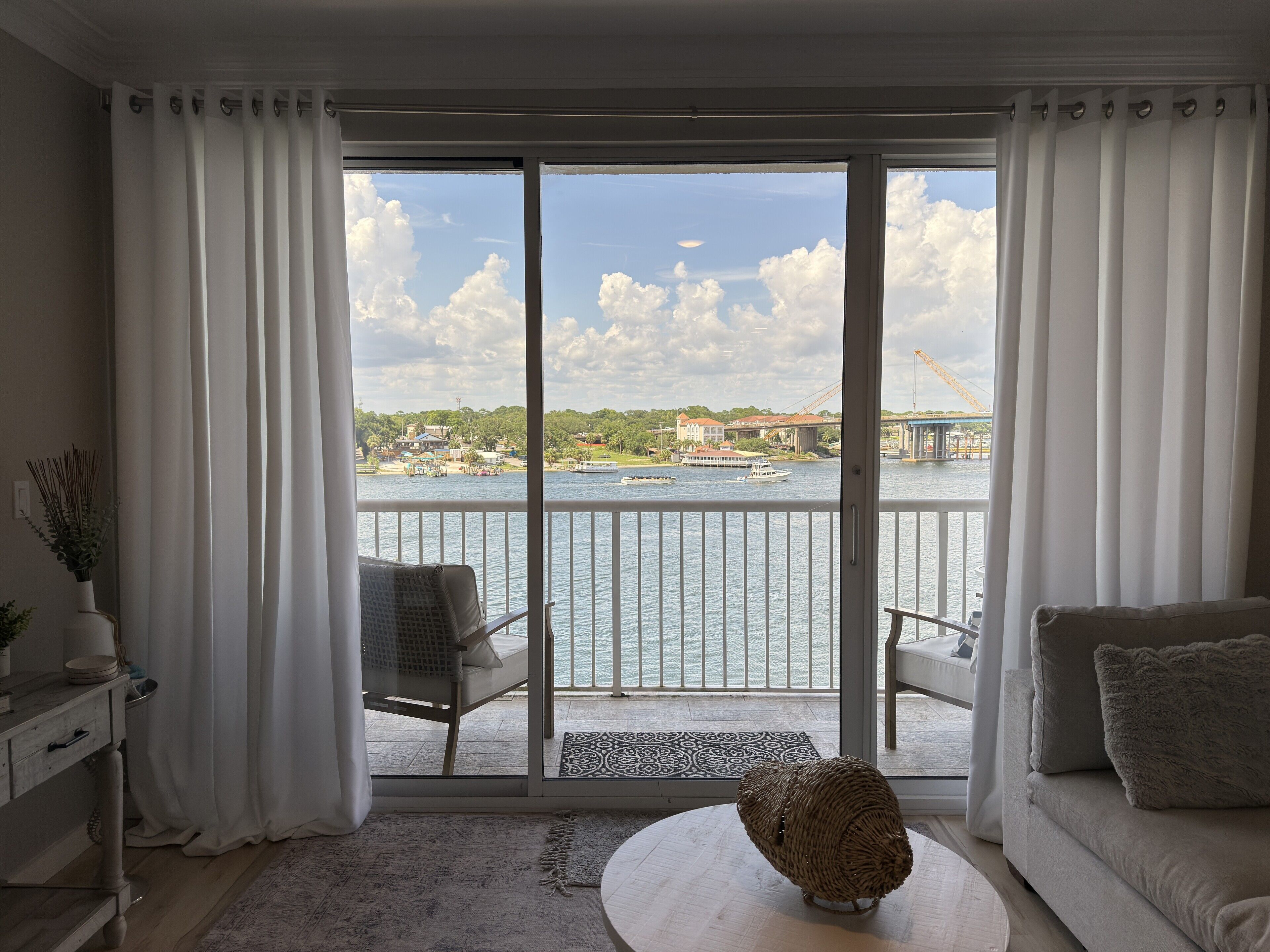 A living room with a view of a river, a balcony with a chair, and a sofa.