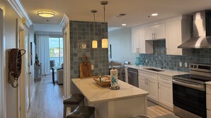 A modern kitchen with white cabinets, a stainless steel range hood, and a built-in oven.