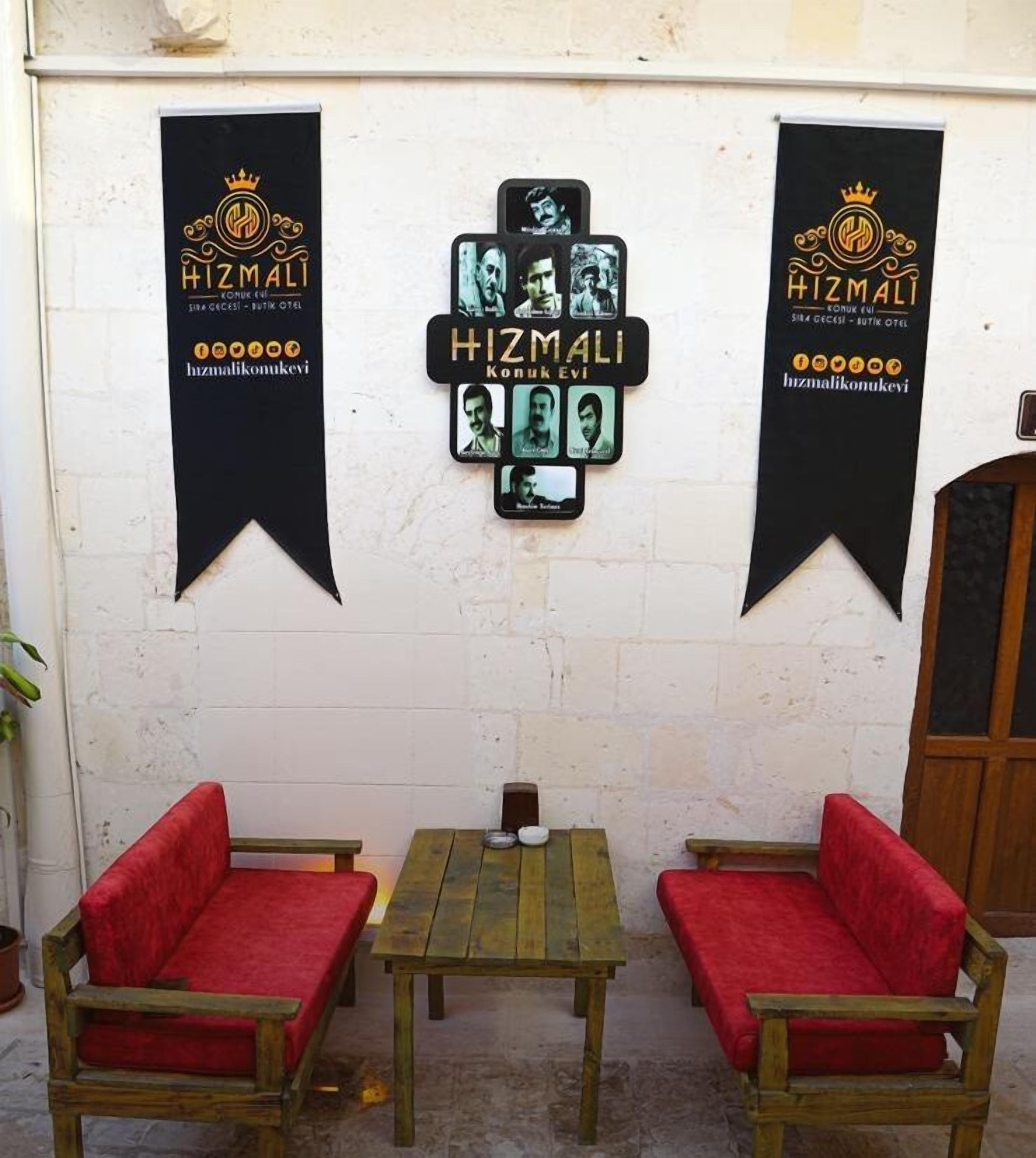 Un mur orné de trois bannières et agrémenté de deux fauteuils rouges à coussins, devant une table en bois.