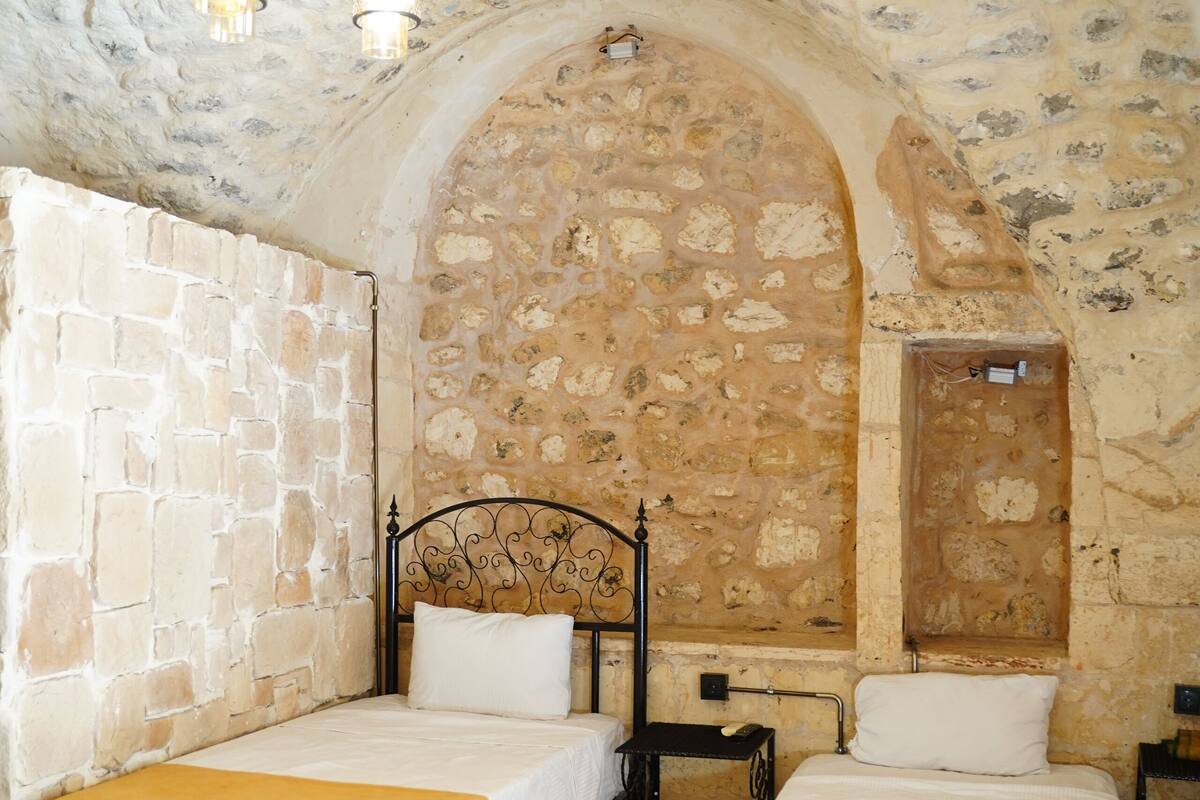 Una habitación con dos camas, paredes de piedra y techo rústico.