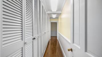Un couloir avec des placards à persiennes blanches et un plancher en bois.