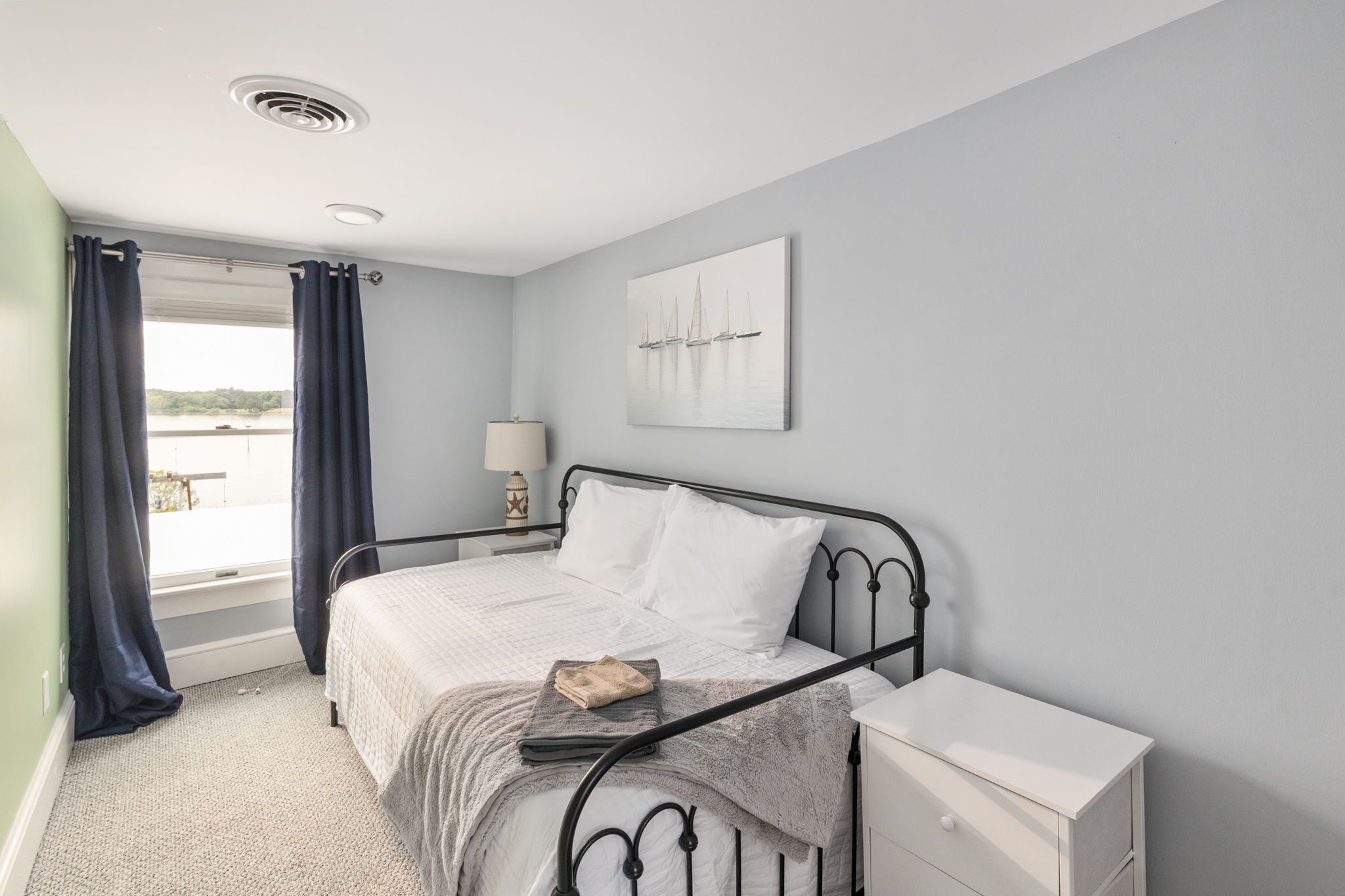 A bedroom with a bed, a bedside table, a lamp, and a window with curtains.
