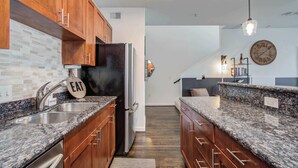 A modern kitchen with granite countertops, wooden cabinets, and a stainless steel refrigerator.