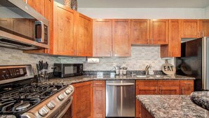 A modern kitchen with wooden cabinets, a stainless steel dishwasher, a gas stove, and a microwave.