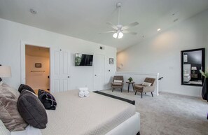 A bedroom with a bed, a TV, a ceiling fan, and a seating area with chairs and a small table. - Midtown Urban Retreat | 2story 1BD/1.5BA Apartment (Houston)