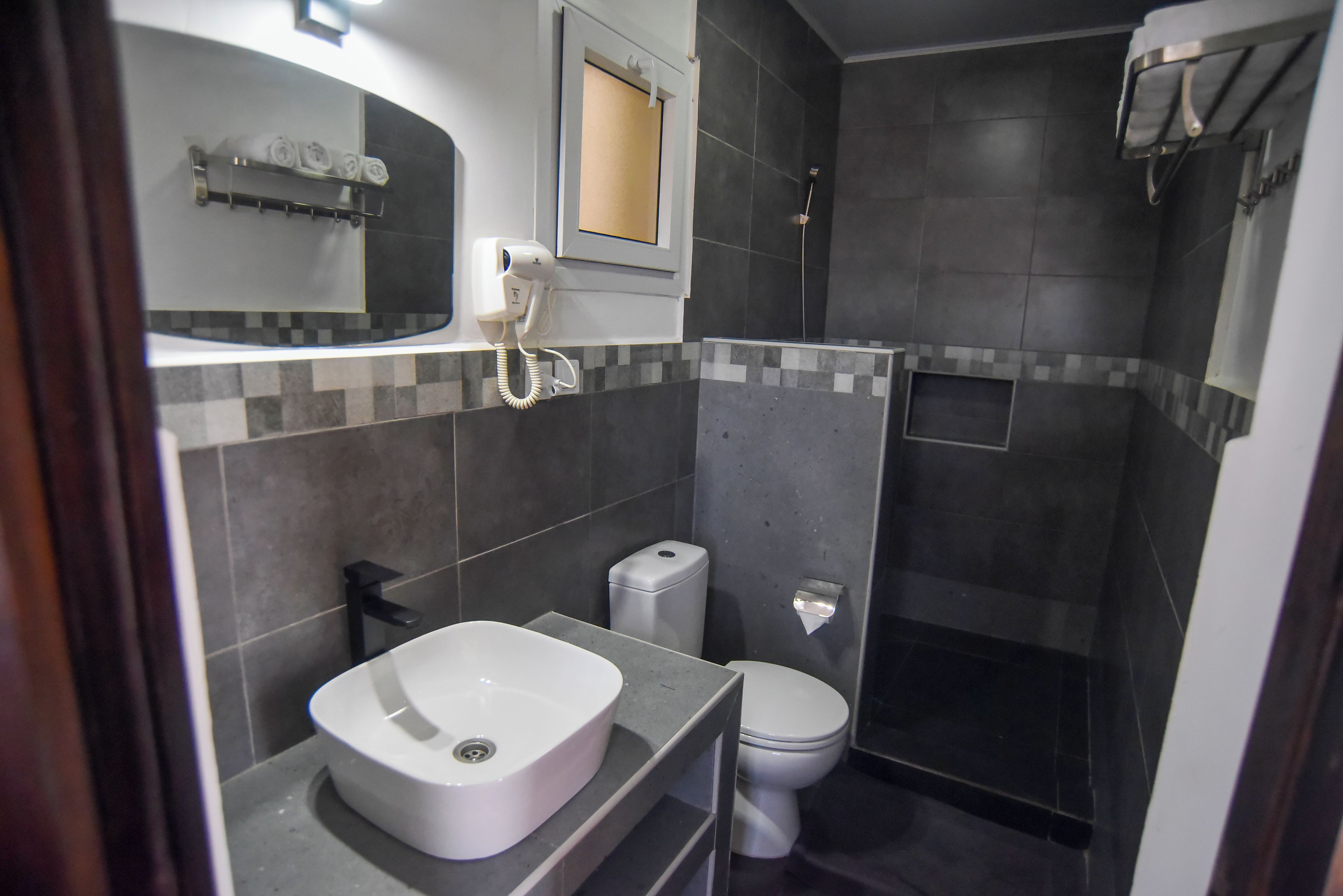 Une salle de bain avec un lavabo blanc, des toilettes et un espace douche.