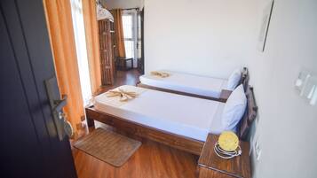 A room with two wooden beds, a small table with a woven basket, and a door with a curtain.