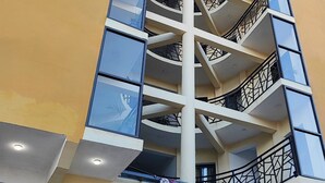 A hotel with a modern design, featuring a central staircase, multiple balconies, and large windows. - Hôtel H1 Fianarantsoa (Fianarantsoa)