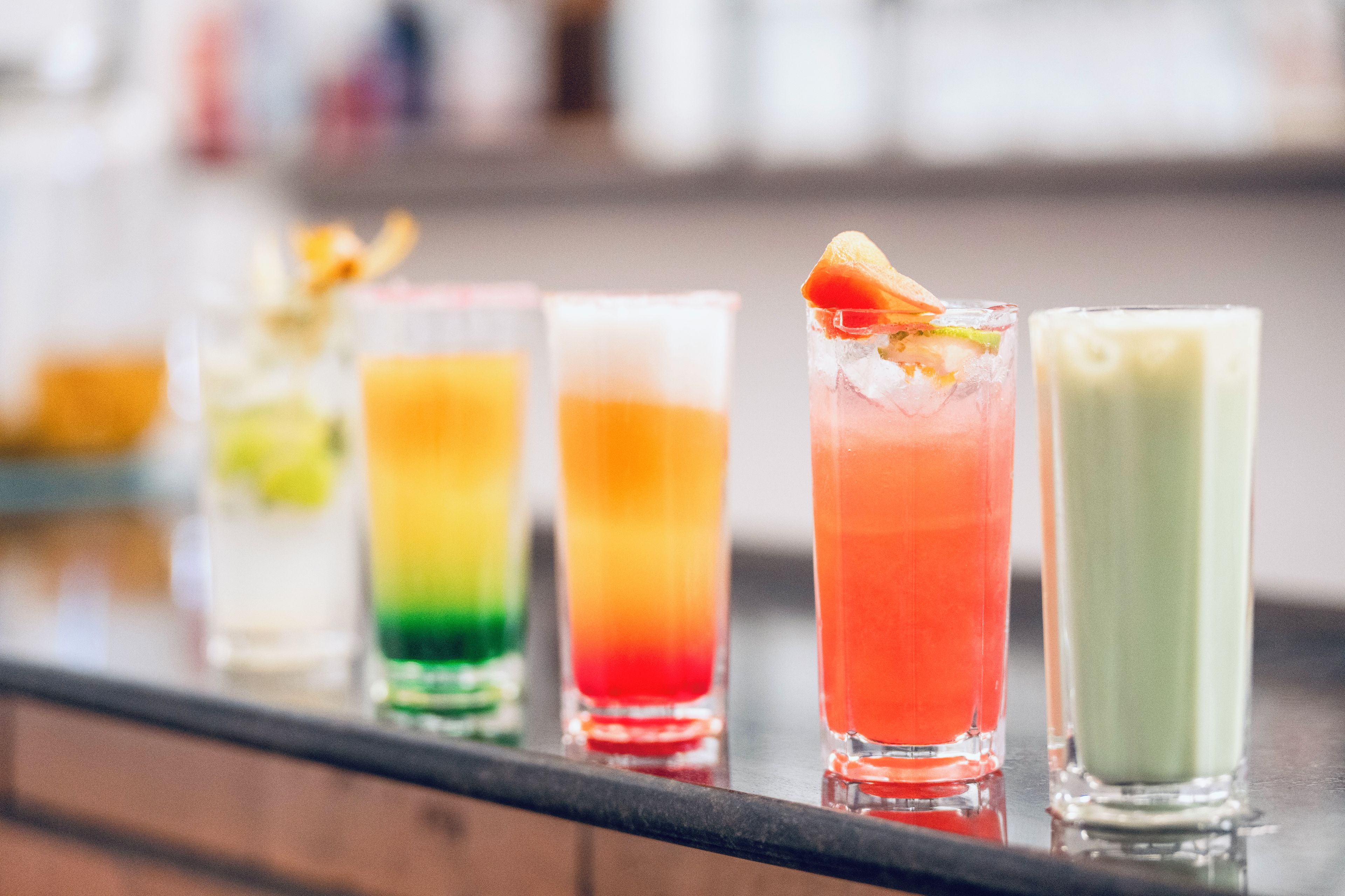 Un bar con diversas bebidas coloridas en vasos altos.