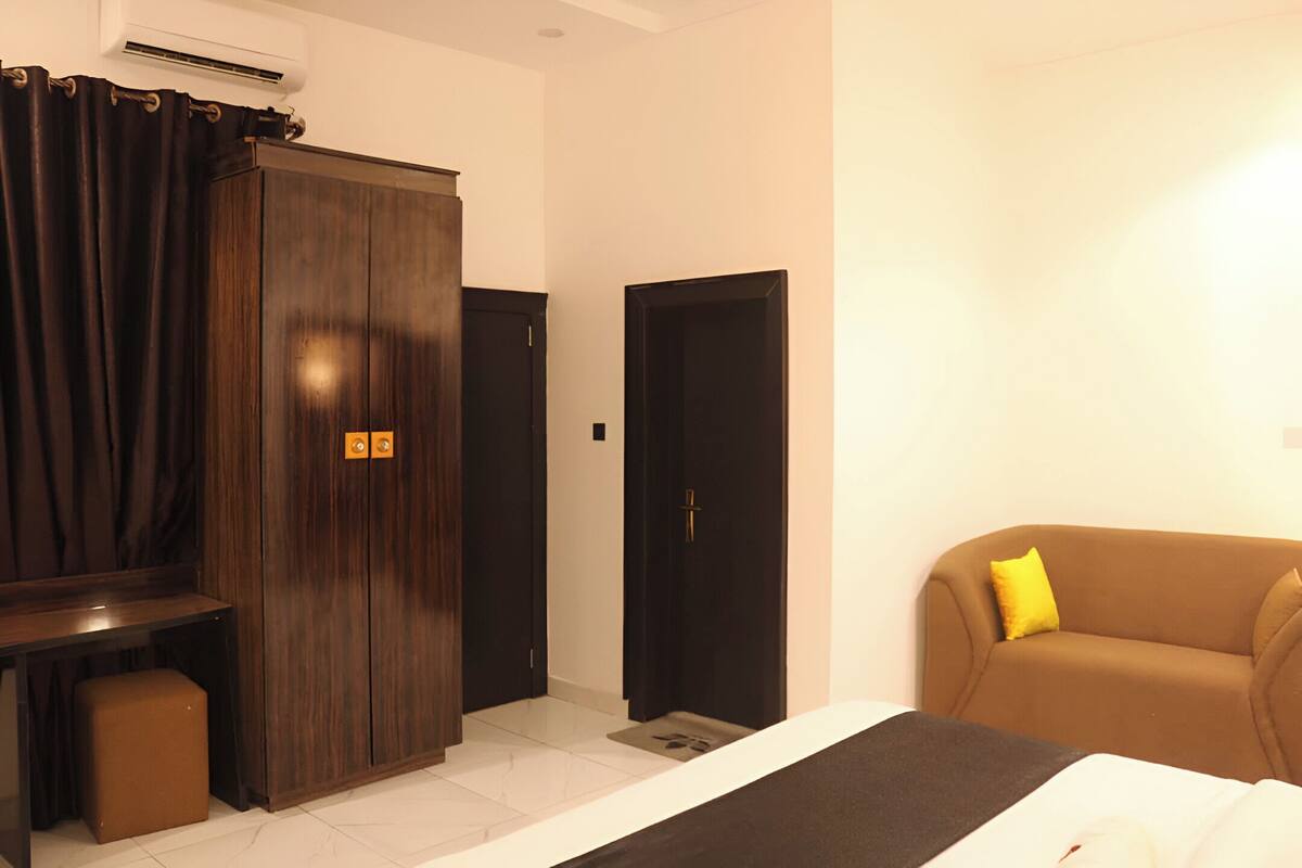 Una camera d'albergo con un letto, un armadio, un divano e un piccolo tavolo.