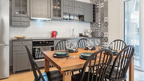Une cuisine moderne avec des meubles gris, un four encastré et un coin repas avec une table en bois, dressée pour quatre personnes.