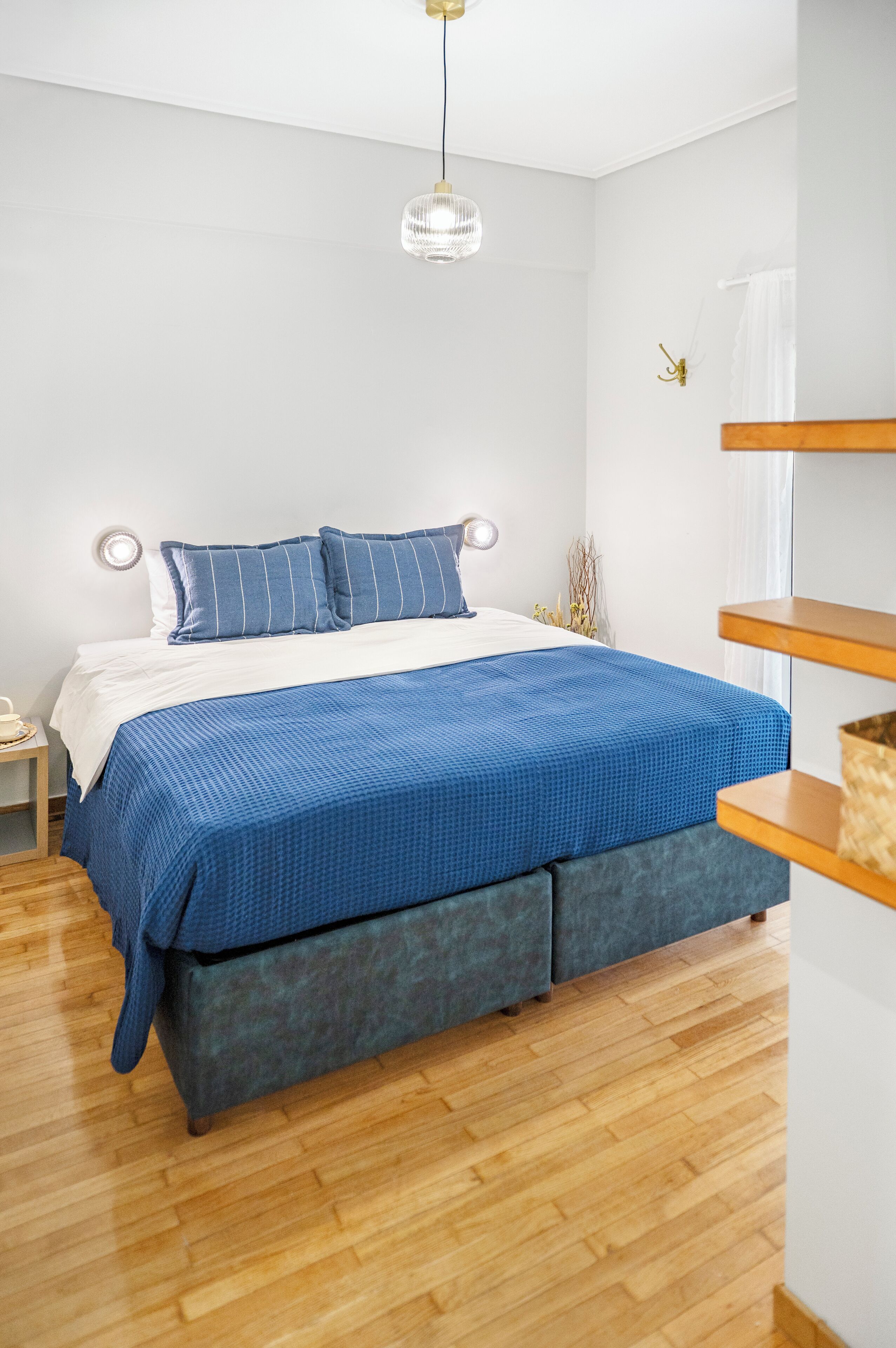 Un dormitorio con cama, mesita de noche, lámpara y una lámpara colgante.