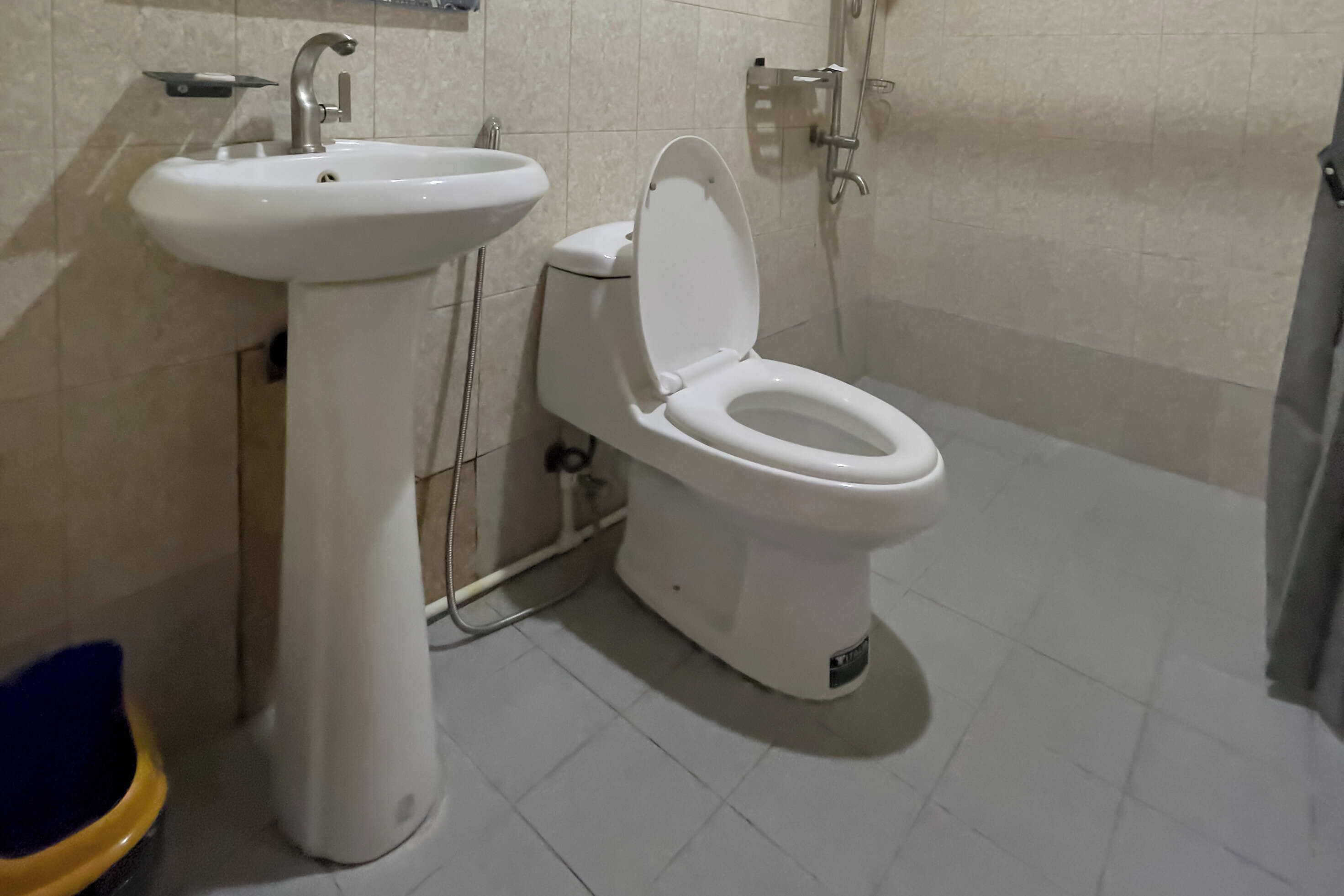 Un baño con lavamanos, inodoro y ducha blancos.