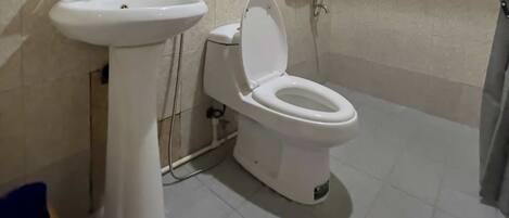 Un baño con lavamanos, inodoro y ducha blancos.