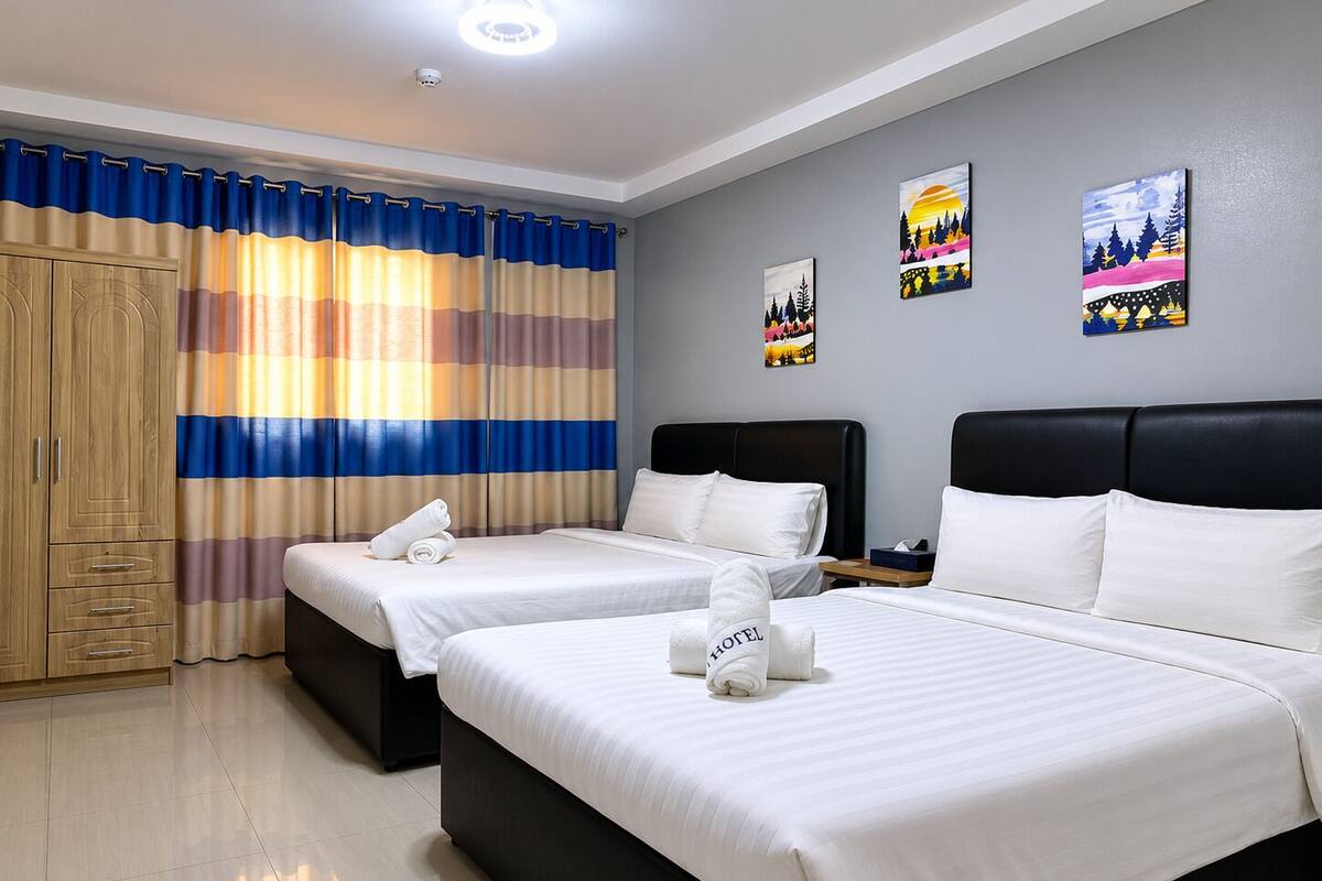 A hotel room with two beds, a wardrobe, and artwork on the wall.