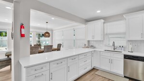 Una cocina moderna con armarios blancos, lavavajillas de acero inoxidable y un banco empotrado.