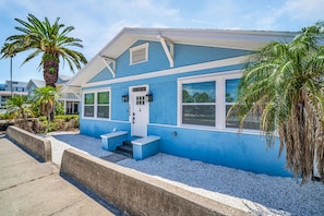 Una casa azul con puerta y ventanas blancas, y un pequeño porche.