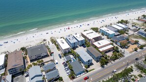 An aerial view of a coastal area with a beach, buildings, and a road.