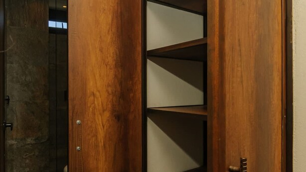 Een houten garderobe met meerdere planken en een duwbehandeling.