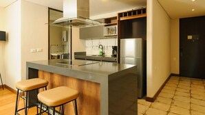 Een moderne keuken met een centraal eiland, barkrukken, een magnetron en een koelkast.