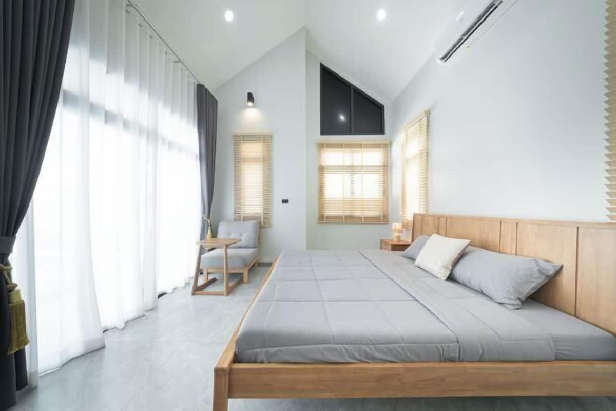 A modern bedroom with a large bed, a small table, and a chair.