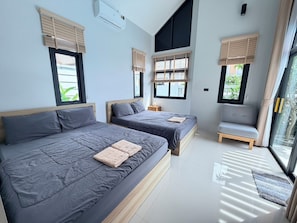 Een moderne slaapkamer met twee bedden, een bank en grote ramen met zonwering.