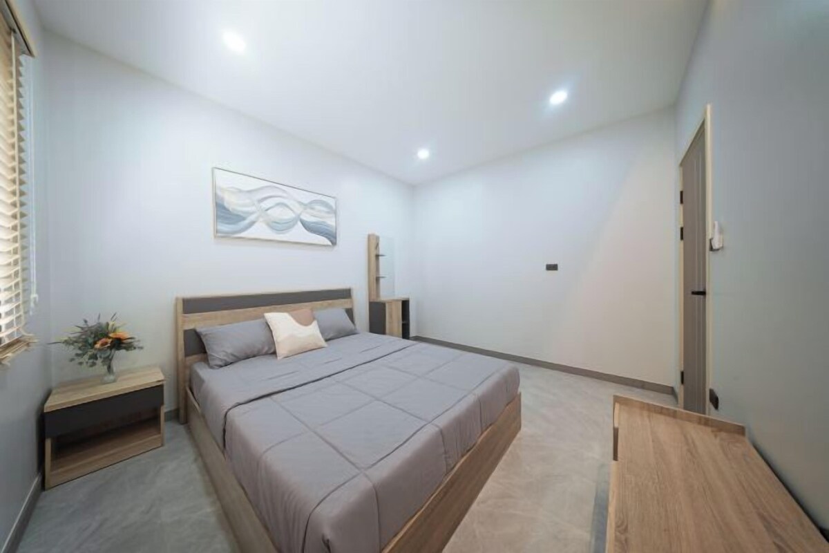 Un dormitorio moderno con cama, mesitas de noche, una obra de arte colgada en la pared y una puerta.