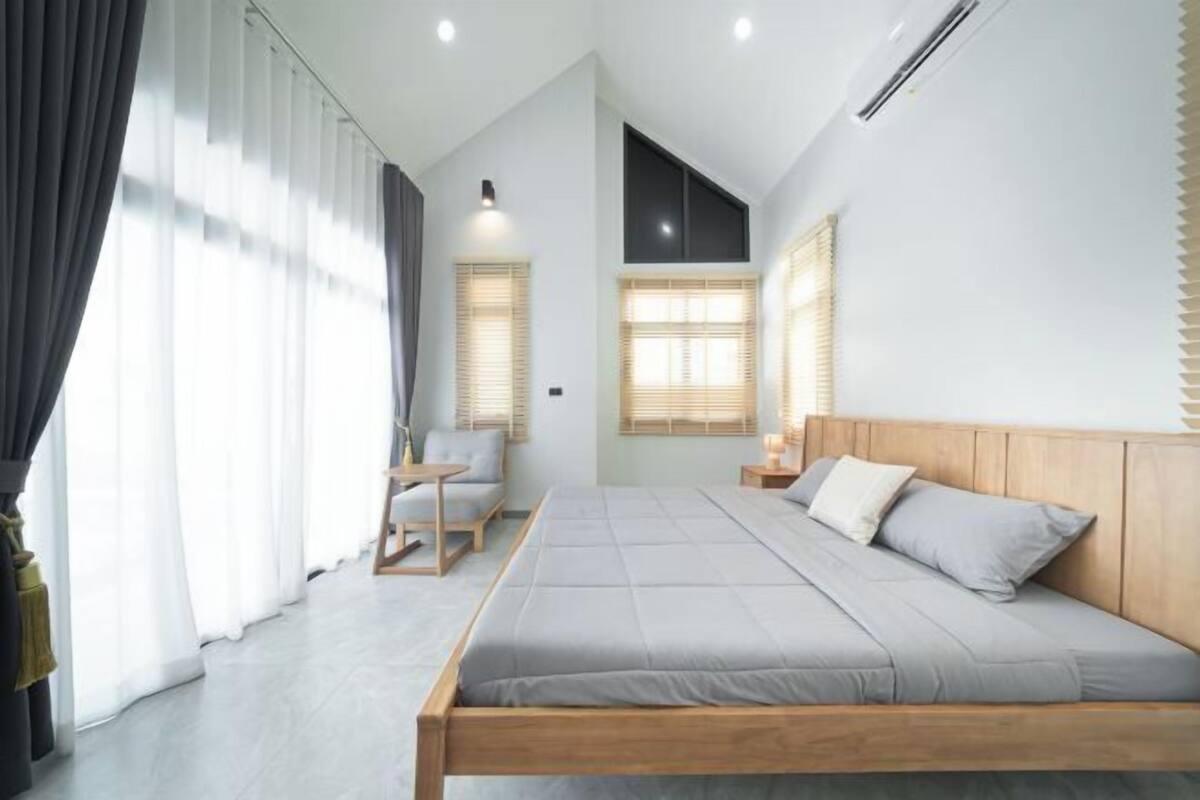 A modern bedroom with a large bed, a small table, and a chair.