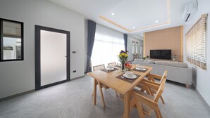 Un salon moderne comprenant un coin repas, un canapé, un téléviseur et une fenêtre avec des rideaux.