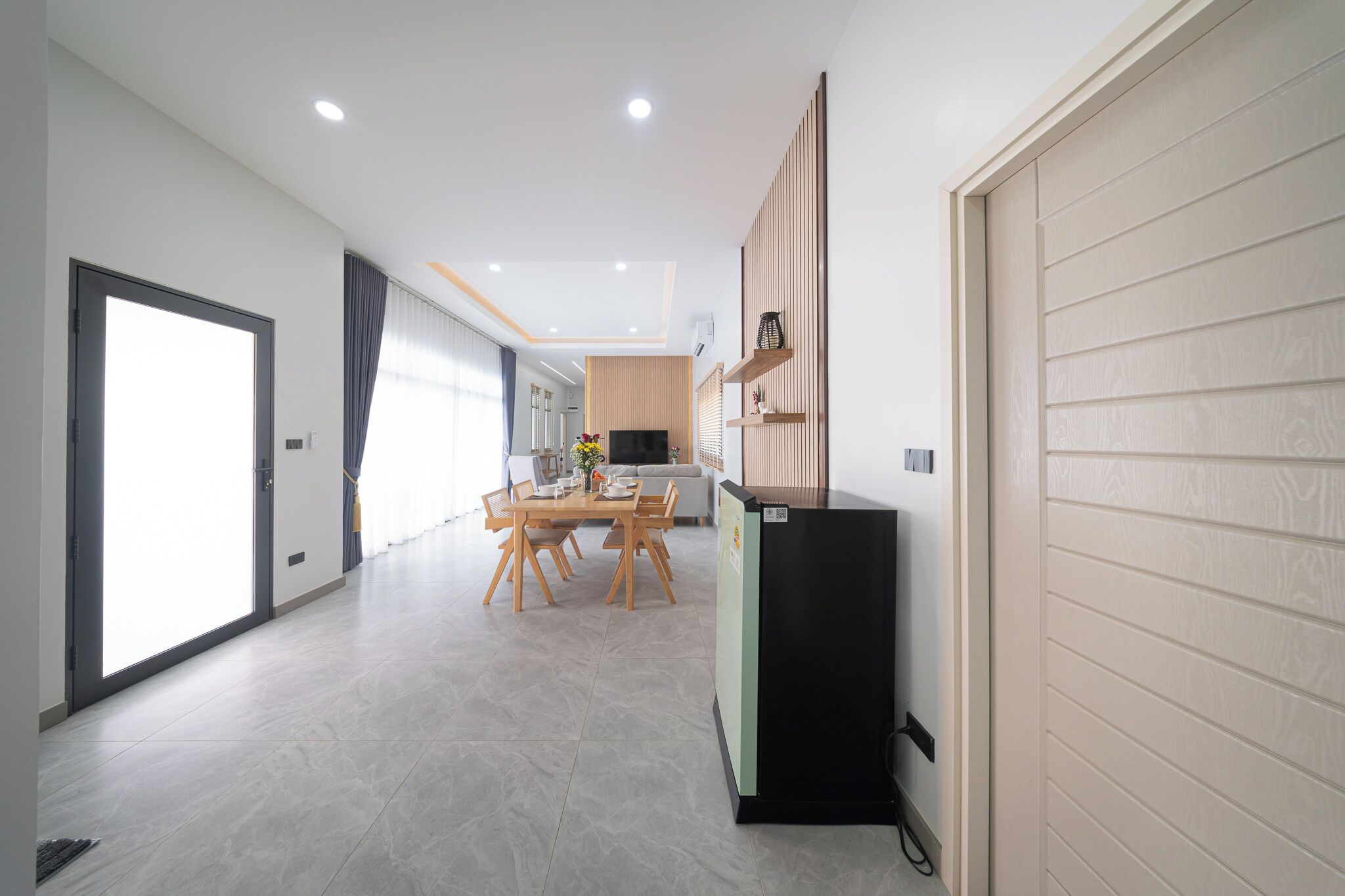 A modern interior with a dining area, kitchen, and a large sliding door.