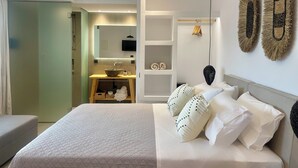 Une chambre moderne avec un grand lit, une table de chevet, un miroir et un téléviseur fixé au mur.