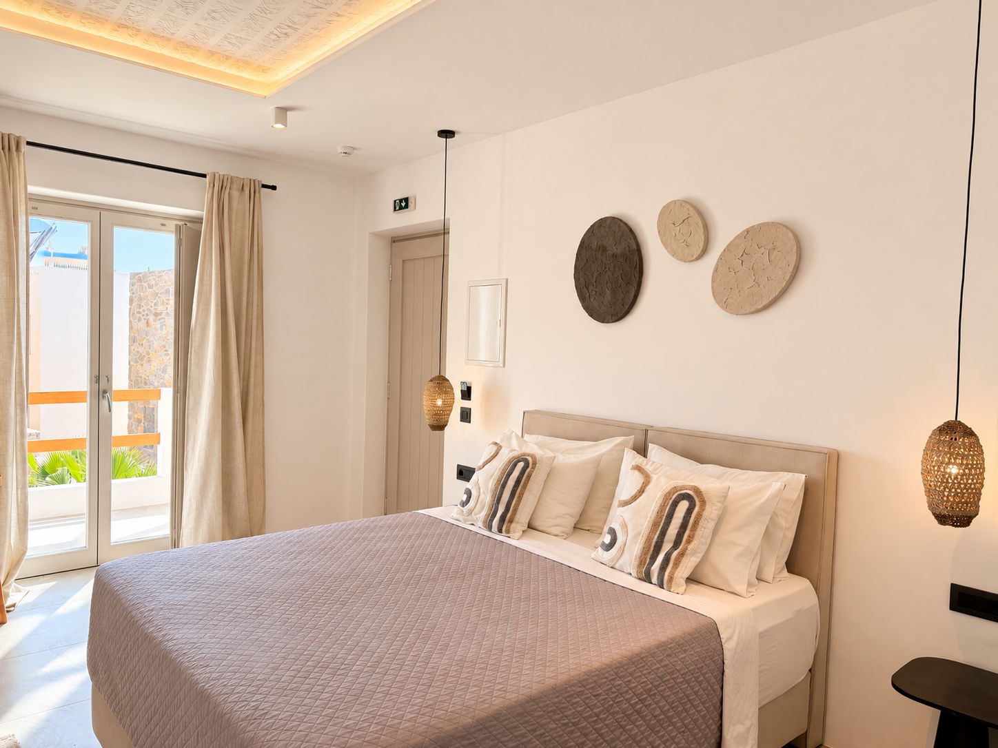 Ein Schlafzimmer mit einem großen Bett, einer Glastür, die auf einen Balkon führt, und einer Wandleuchte.
