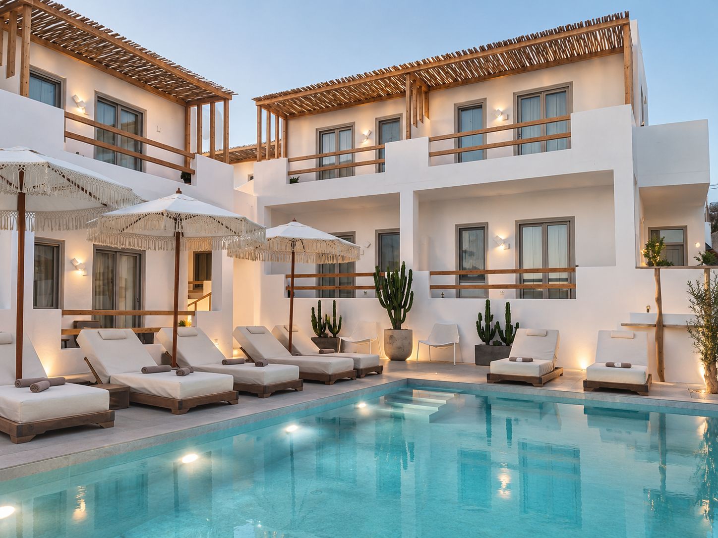 Un hotel moderno con piscina, diversi balconi e lettini prendisole.